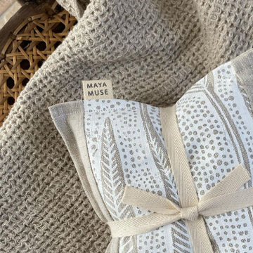 Maya Muse Wheat Heat Bag – Linen & Lavender, Barangaroo Print folded in half and tied with a ribbon on beige blanket
